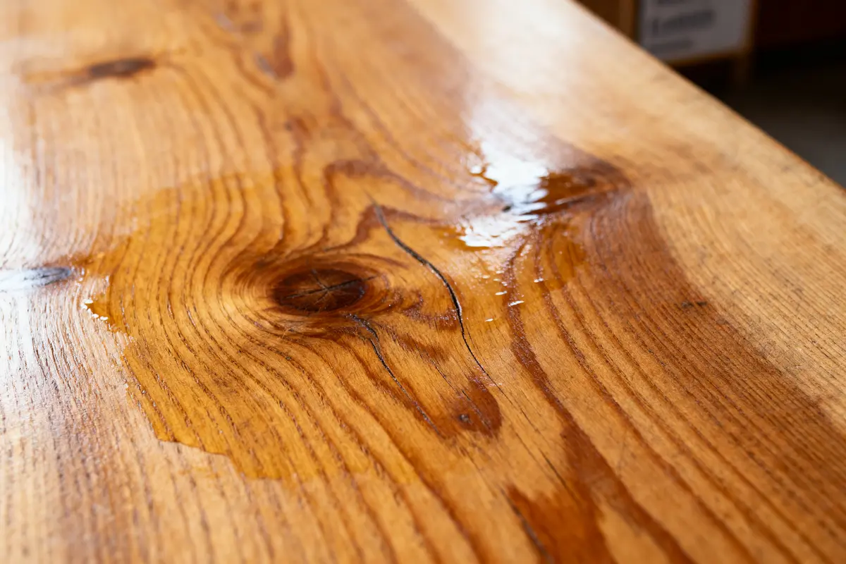 Gros plan sur une surface en bois verni avec des cernes et des traces d'humidité visibles.