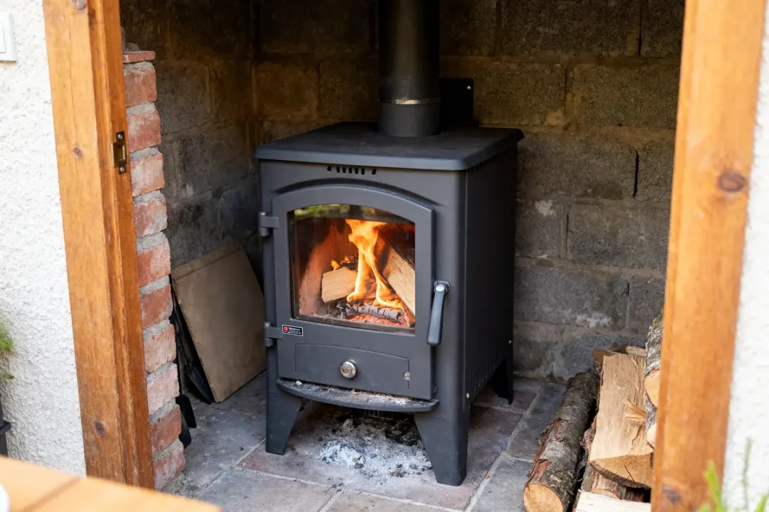 Poêle à bois dans cheminée avec bûches de bois et flammes ardentes visibles