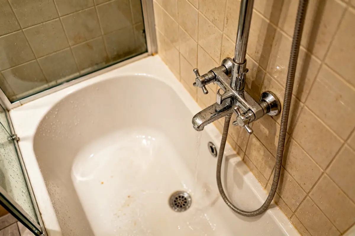 Robinet de baignoire dans salle de bain avec douche italienne et paroi vitrée