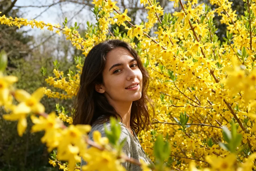 Personne souriante devant de magnifiques fleurs jaunes de forsythia en pleine floraison