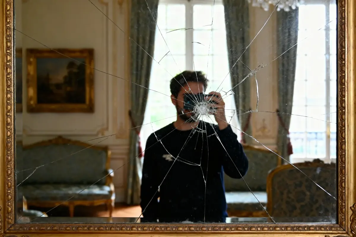 Personne photographiant son reflet dans un miroir cassé dans un salon élégant