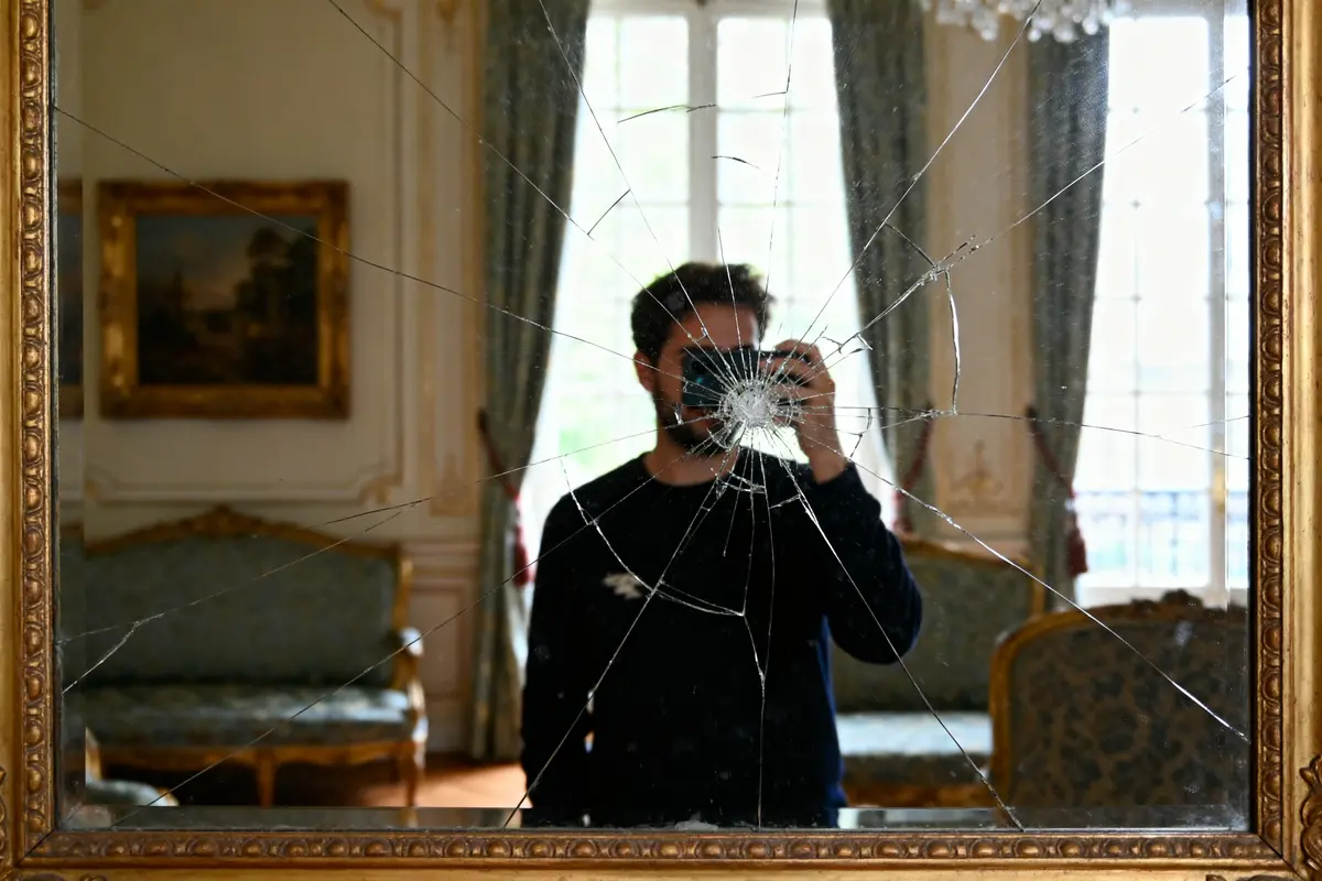 Personne photographiant son reflet dans un miroir cassé dans un salon élégant