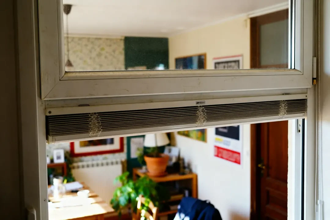 Fenêtre PVC aération dans une pièce avec décorations et plantes visibles au fond