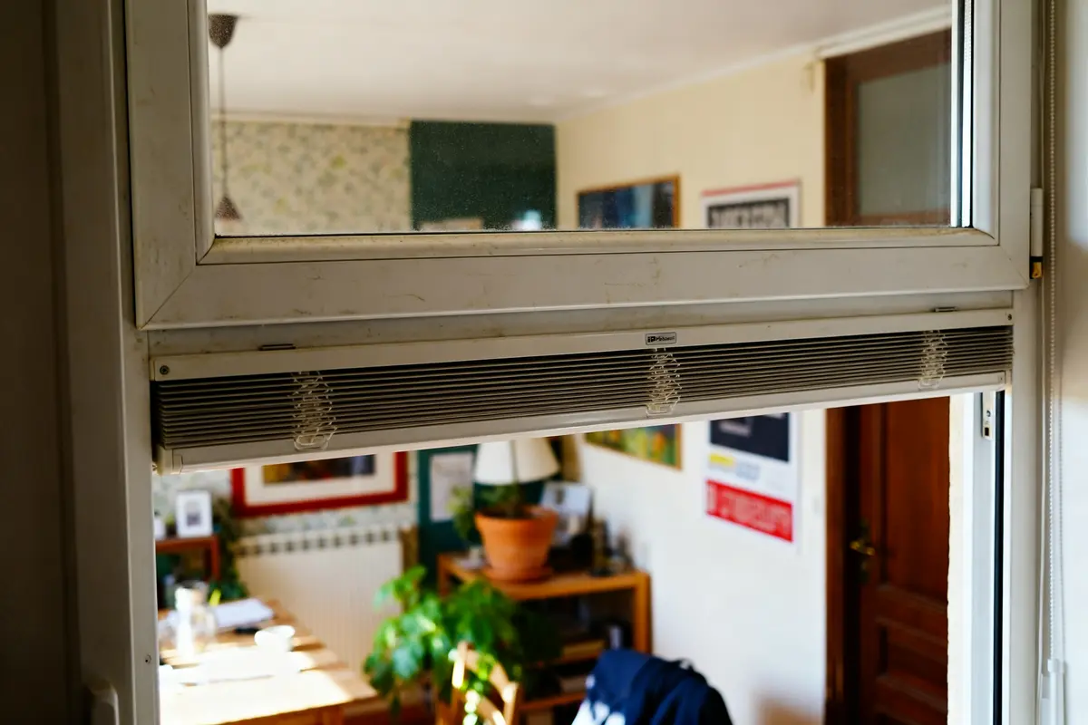 Fenêtre PVC aération dans une pièce avec décorations et plantes visibles au fond
