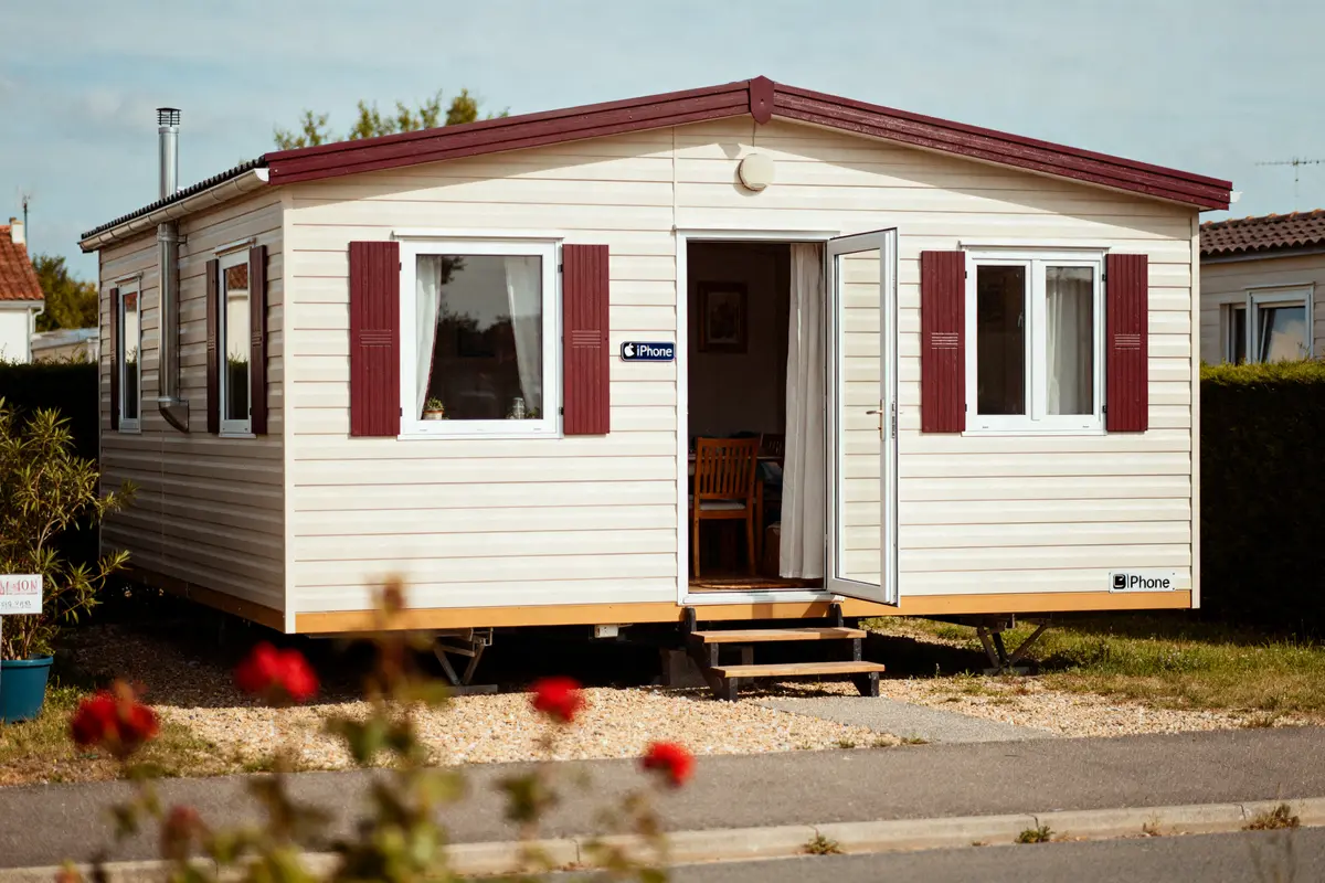 Maison en préfabriqué blanche avec jardin et porte ouverte accueillante