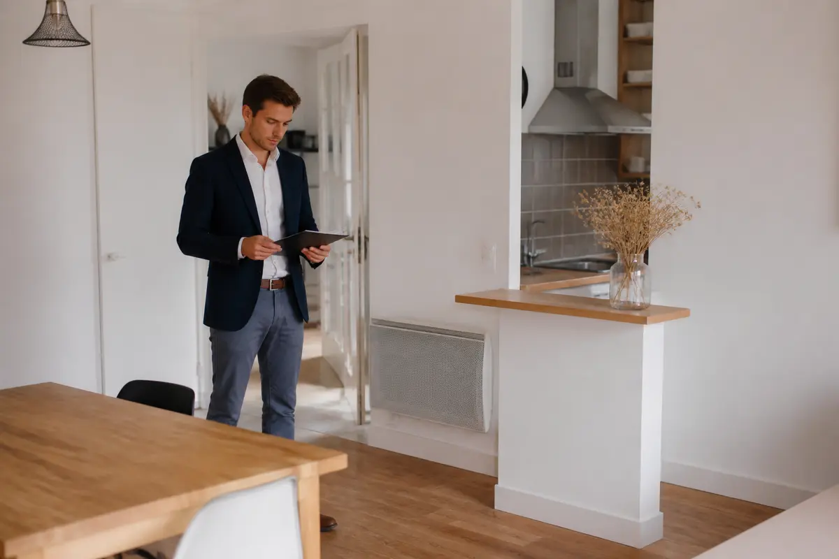 Un homme en costume lit une tablette numérique dans un intérieur moderne et lumineux.